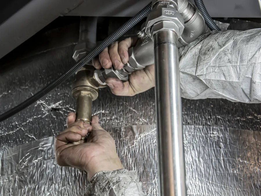 Plumber fitting a pipe under a sink